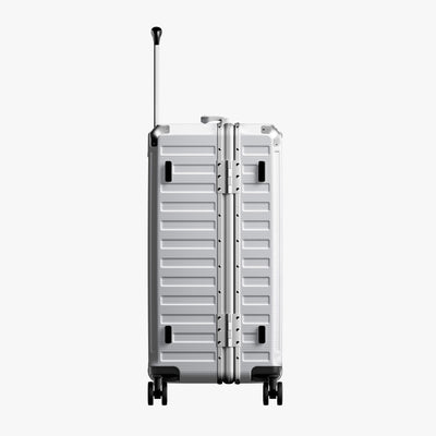Side view of 24'' aluminum frame trunk luggage with a 4:6 trunk structure and protective foot pads that prevent scratches and wear when placed on the ground.  