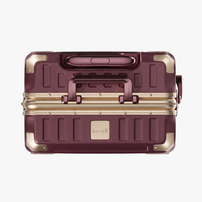Side view of aluminum frame luggage with protective foot pads that elevate the shell and prevent scratches when the suitcase is placed on the ground. #show #color_cherry