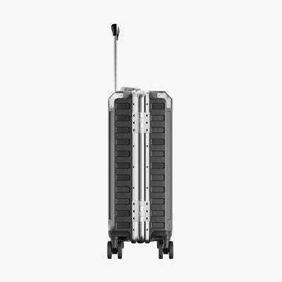 Side view of aluminum frame luggage with protective foot pads that elevate the shell and prevent scratches when the suitcase is placed on the ground. #show #color_charcoal