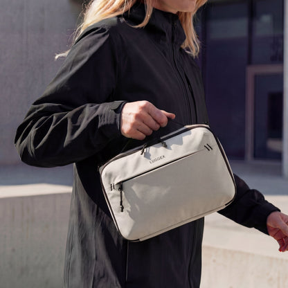 LUGGEX lightweight convertible crossbody organizer bag in beige, carried by hand for everyday travel and urban use 