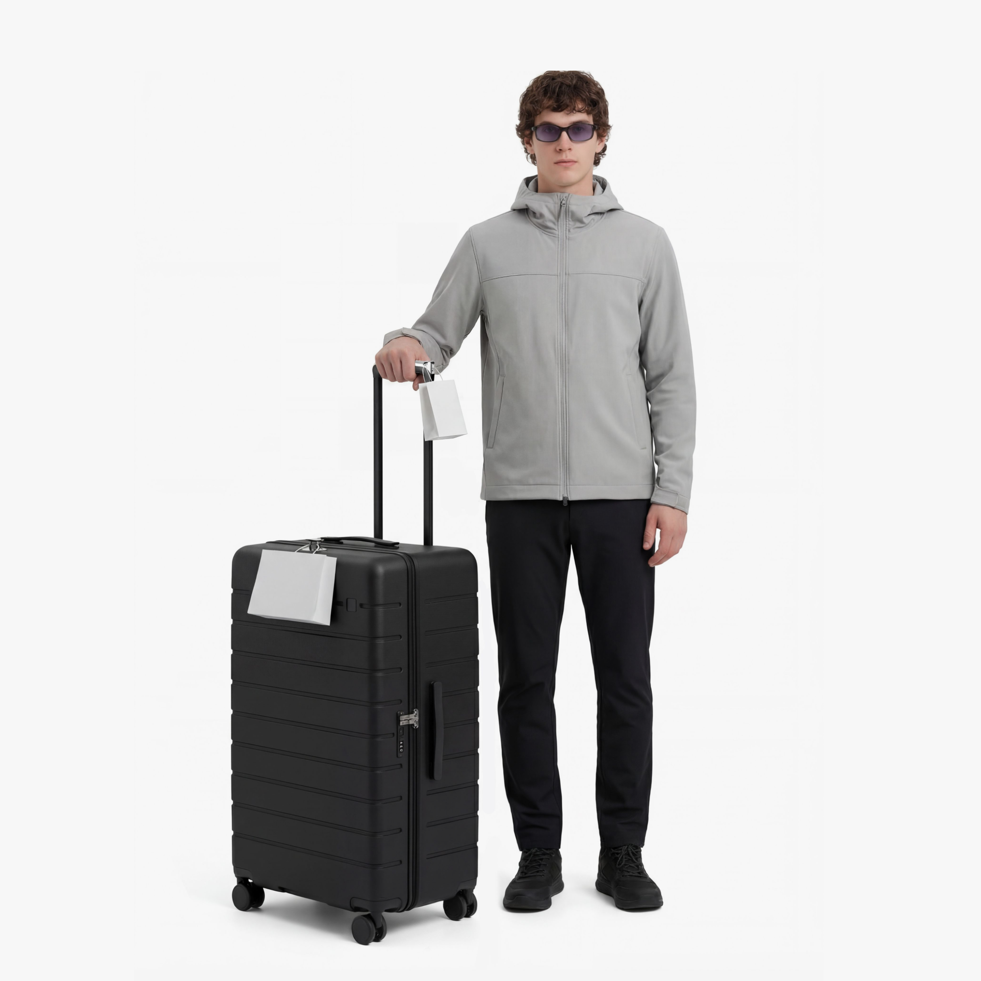 Traveler standing with HUP 30-inch trunk check-in luggage, showing full-size capacity, smooth rolling wheels, and easy handling during travel. #color_black