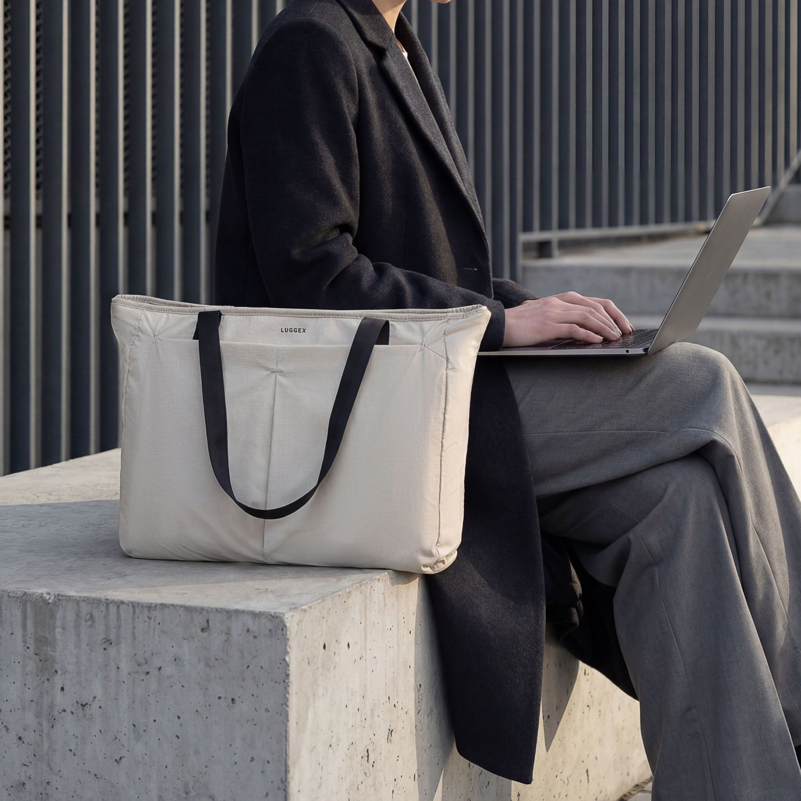 LUGGEX 15.6” laptop tote bag used in a professional work setting, shown beside a laptop outdoors. 